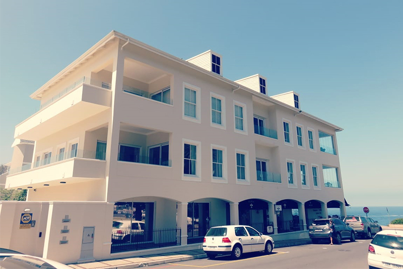 Coastal estate exterior with fresh paint finish overlooking Walker Bay